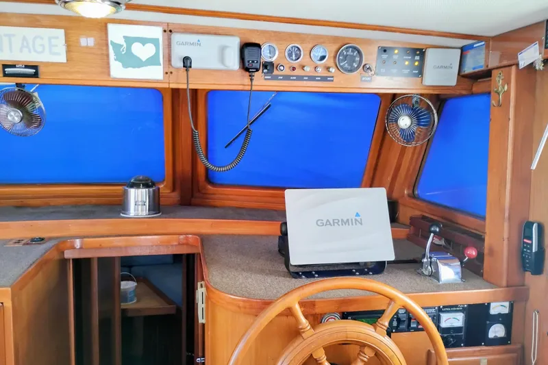 Slide: The Image of 1978 Puget 38 Europa Trawler helm with Garmin navigation, wooden wheel, and control panel. - 38