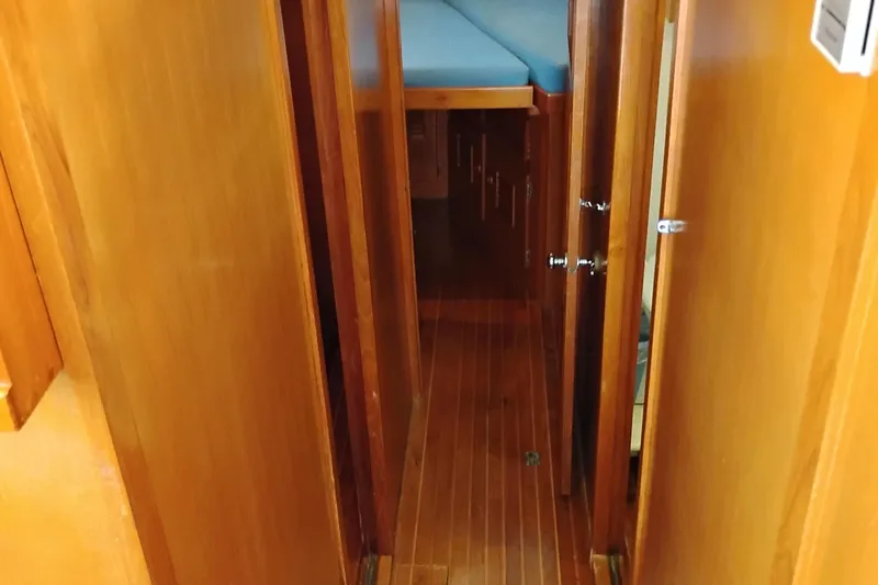 Slide: The Image of 1978 Puget 38 Europa Trawler interior hallway with wooden paneling and blue bedding. - 51