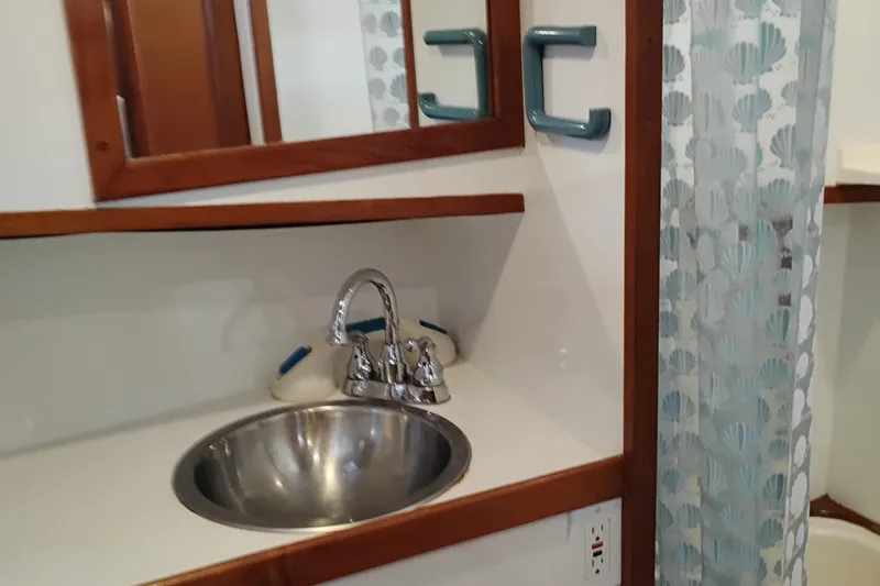 Slide: The Image of 1978 Puget 38 Europa Trawler bathroom with sink, mirror, and patterned shower curtain. - 54