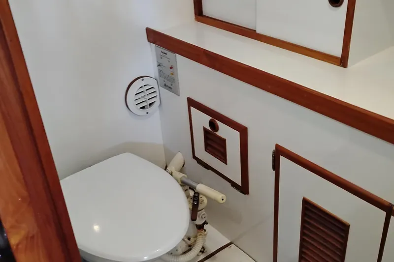 Slide: The Image of 1978 Puget 38 Europa Trawler bathroom with white toilet and wooden accents. - 55