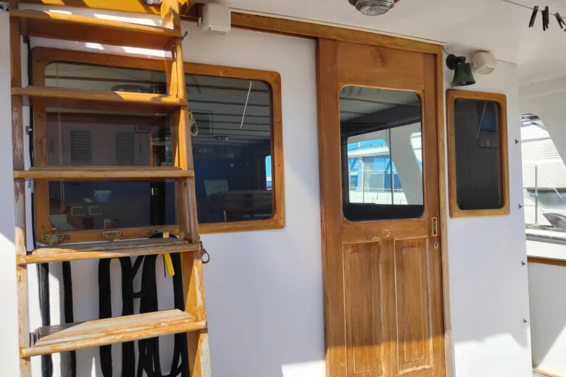 Slide: The Image of 1978 Puget 38 Europa Trawler with wooden ladder and door, docked at marina. - 9