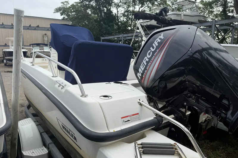 Slide: The Image of 2017 Boston Whaler 170 Dauntless boat with Mercury engine, covered seats, parked outdoors. - 2