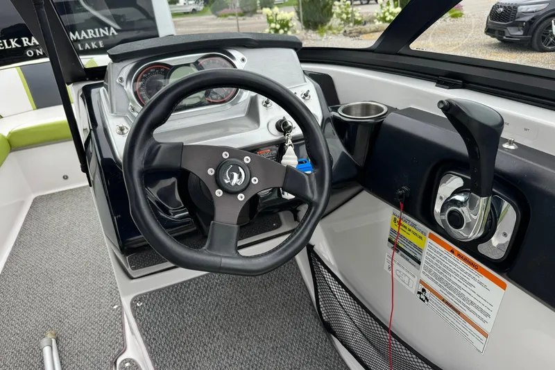 Slide: The Image of Steering wheel and controls of a 2015 Scarab 195 boat, featuring a modern dashboard. - 10