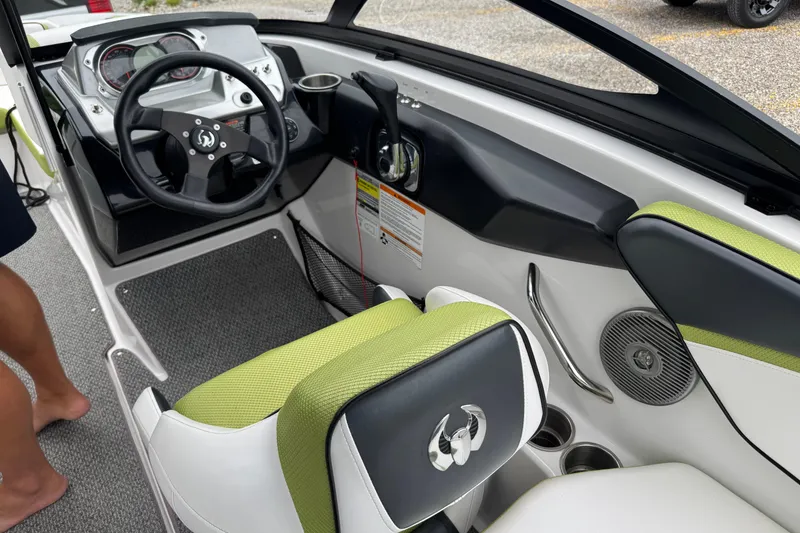 Slide: The Image of Interior of a 2015 Scarab 195 boat featuring steering wheel and green-accented seating. - 11