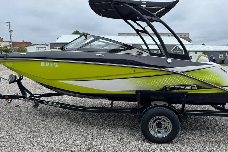 Slide: The Image of 2015 Scarab 195 boat in vibrant green on a trailer, parked on gravel. - 6