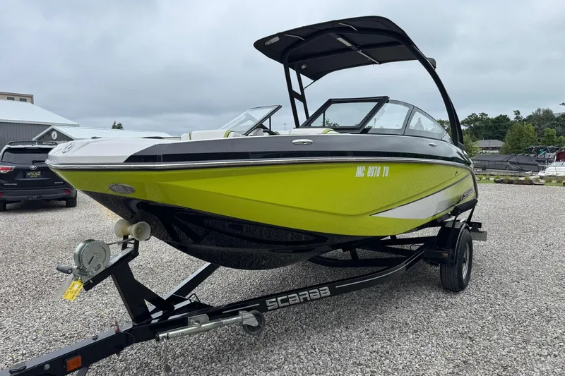 Slide: The Image of 2015 Scarab 195 boat in vibrant green on a trailer, parked outdoors. - 7