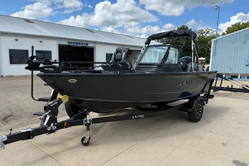 Slide: The Image of 2026 Lund 1775 Impact XS Sport boat on trailer outside showroom, under a cloudy sky. - 3