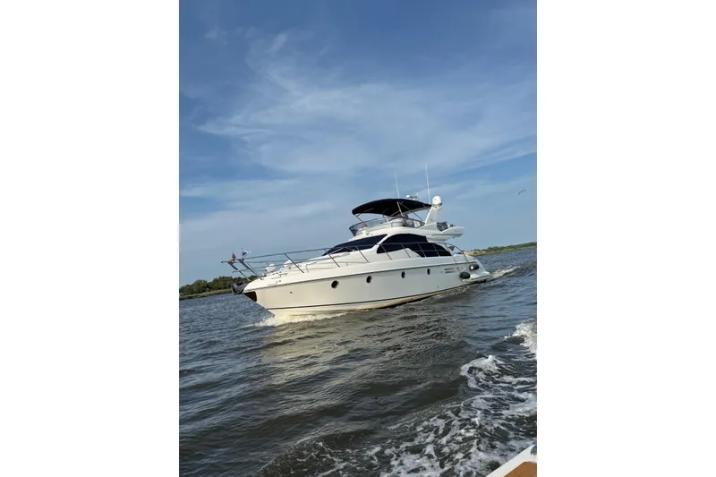 Slide: The Image of 2008 Azimut 55 Fly yacht cruising on open water under a clear blue sky. - 2