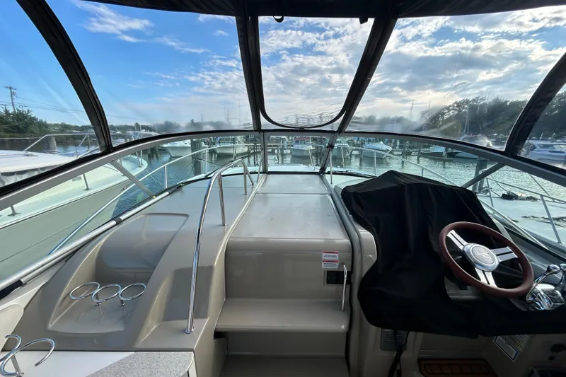Slide: The Image of 2010 Sea Ray Sundancer 330 cockpit with steering wheel, marina view, and clear skies. - 16
