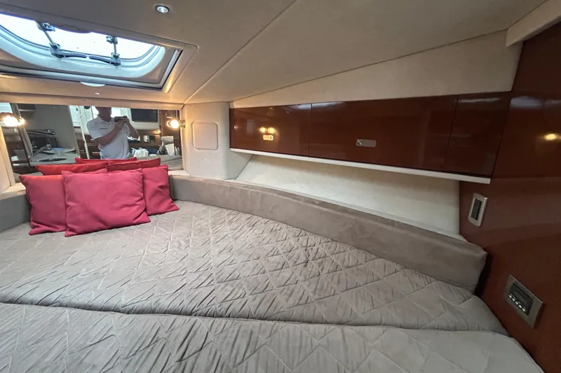 Slide: The Image of 2010 Sea Ray Sundancer 330 cabin interior with bed, red pillows, and overhead hatch. - 21