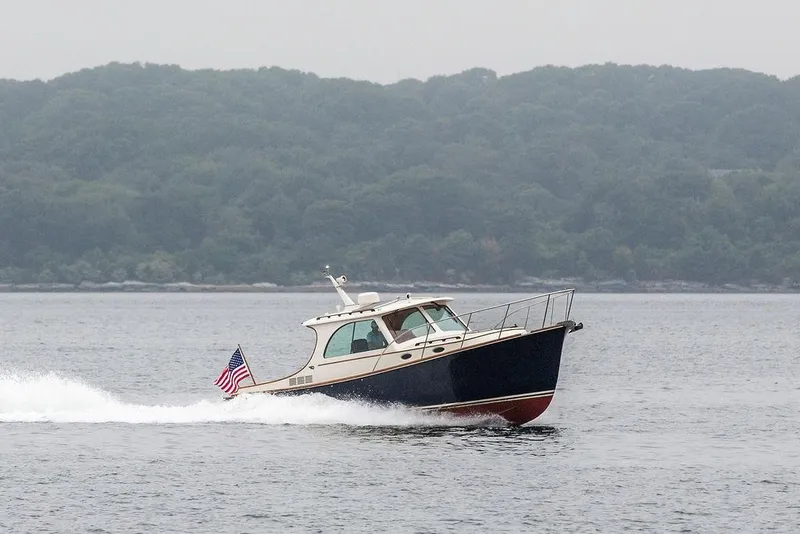 Slide: The Image of 2010 Hinckley Picnic Boat MKIII cruising on a calm lake with forested background. - 1