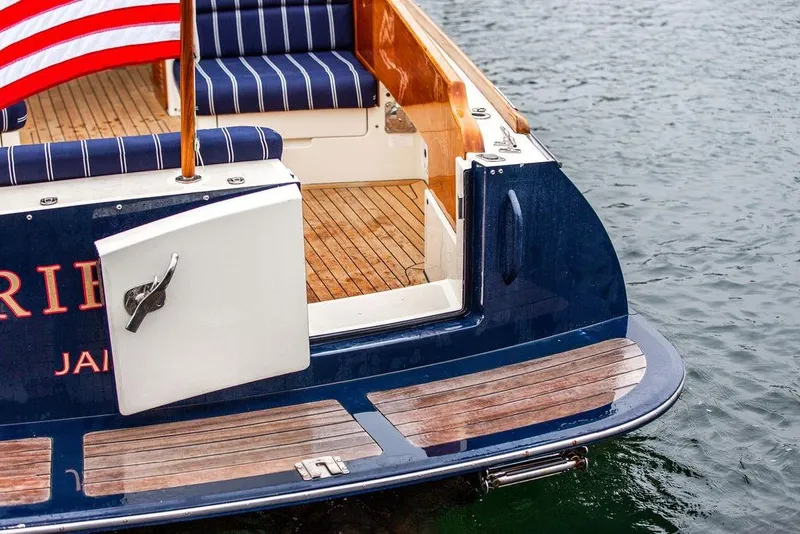 Slide: The Image of Hinckley Picnic Boat MKIII 2010, featuring striped seating and American flag, docked on water. - 16