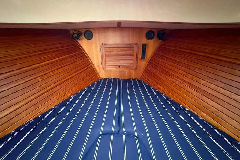 Slide: The Image of Interior of 2010 Hinckley Picnic Boat MKIII with wooden paneling and striped bedding. - 24