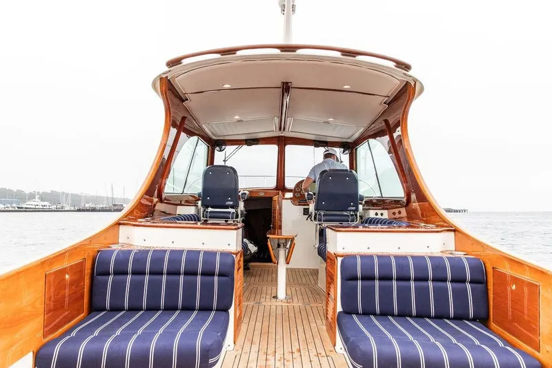 Slide: The Image of Hinckley Picnic Boat MKIII 2010 interior with striped seating and wooden finishes on the water. - 8