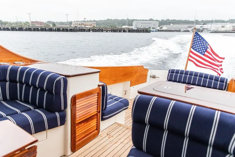 Slide: The Image of Hinckley Picnic Boat MKIII 2010 with striped seating and American flag on open water. - 9