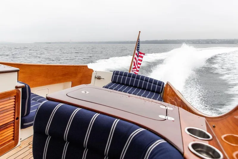 Slide: The Image of Hinckley Picnic Boat MKIII 2010 cruising on water, featuring striped seating and American flag. - 13