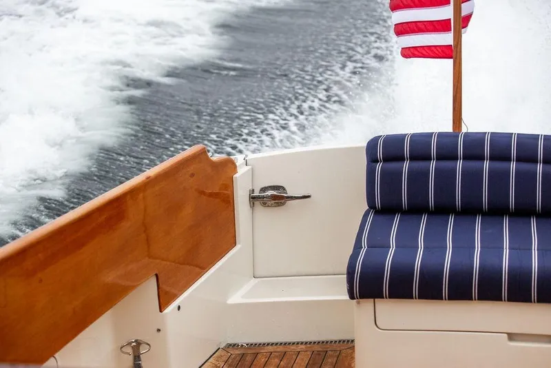 Slide: The Image of Hinckley Picnic Boat MKIII 2010 with striped seating and American flag on water. - 15