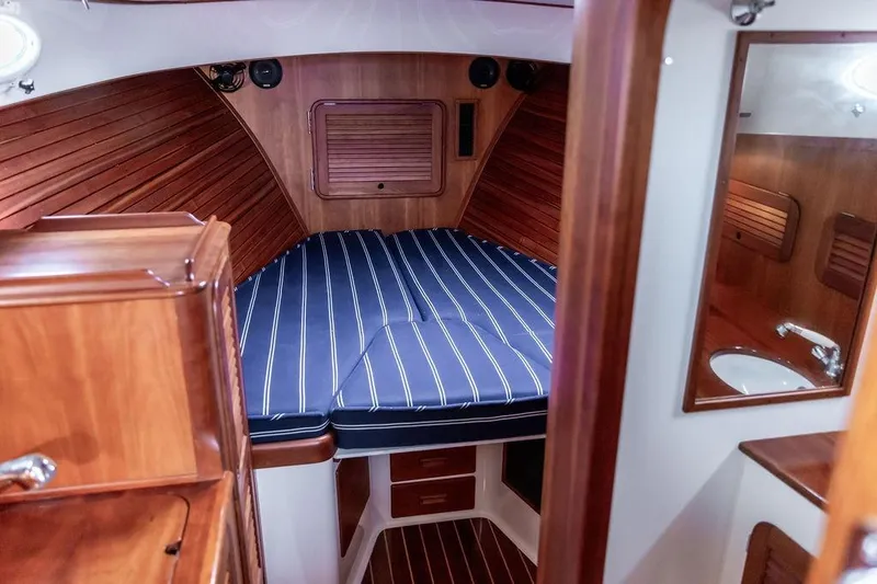 Slide: The Image of Hinckley Picnic Boat MKIII 2010 interior with striped bedding and wooden cabinetry. - 23