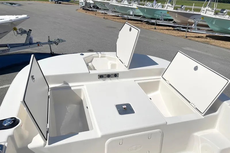 Slide: The Image of 2026 Carolina Skiff 19 LS boat with open storage compartments in a marina setting. - 13