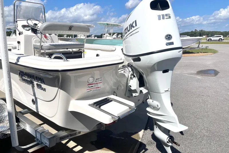 Slide: The Image of 2026 Carolina Skiff 19 LS boat with Suzuki 115 outboard motor, parked on a trailer. - 9