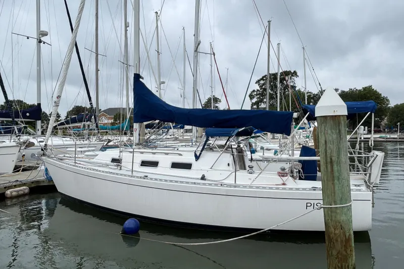 Slide: The Image of 1988 J Boats J/28 sailboat docked in a marina, featuring blue covers and calm waters. - 2
