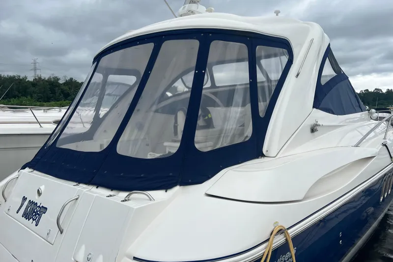 Slide: The Image of 2005 Cruisers Yachts 400 Express with blue canopy, docked under cloudy skies. - 10