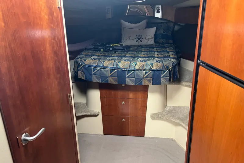 Slide: The Image of 2005 Cruisers Yachts 400 Express cabin with bed, wooden cabinets, and carpeted steps. - 24