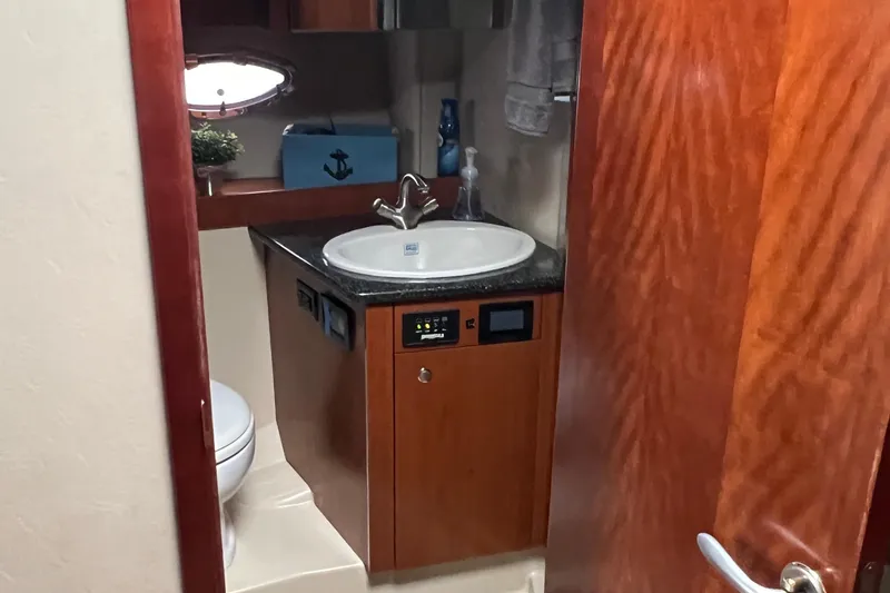 Slide: The Image of 2005 Cruisers Yachts 400 Express bathroom with sink, toilet, and wooden cabinetry. - 26