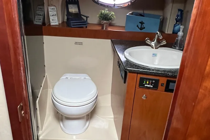Slide: The Image of 2005 Cruisers Yachts 400 Express bathroom with toilet, sink, and nautical decor. - 27