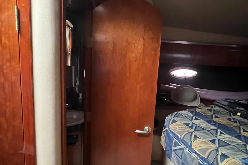 Slide: The Image of 2005 Cruisers Yachts 400 Express cabin interior with wooden door and patterned bedding. - 29