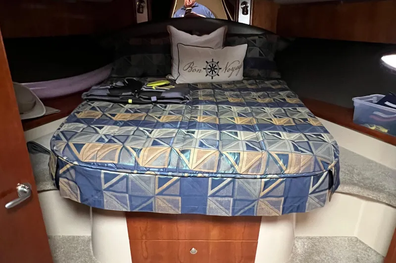 Slide: The Image of 2005 Cruisers Yachts 400 Express cabin with geometric-patterned bedding and nautical-themed pillow. - 31