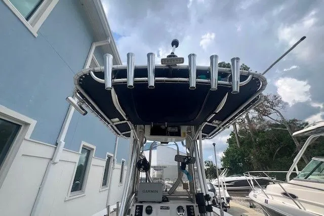 Slide: The Image of 2017 Robalo R200 Center Console boat with T-top and rod holders, docked near a blue building. - 18