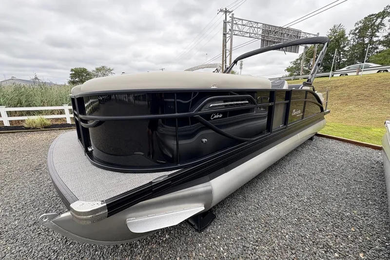 Slide: The Image of 2026 Barletta C22UC pontoon boat on gravel, featuring sleek black and silver design. - 2