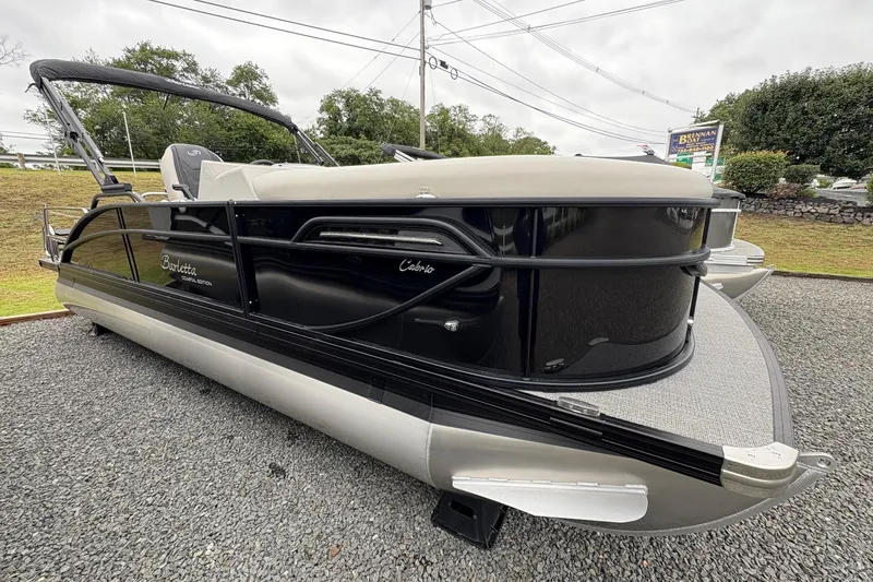 Slide: The Image of 2026 Barletta C22UC pontoon boat displayed on gravel lot, side view. - 4