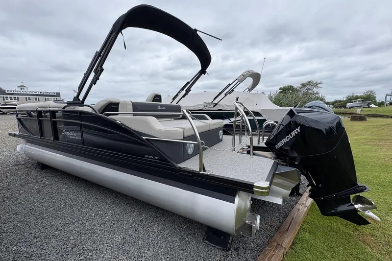 Slide: The Image of 2026 Barletta C22UC pontoon boat with Mercury engine, displayed outdoors on gravel. - 5