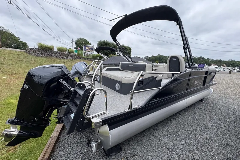 Slide: The Image of 2026 Barletta C22UC pontoon boat with Mercury engine, parked on gravel. - 7
