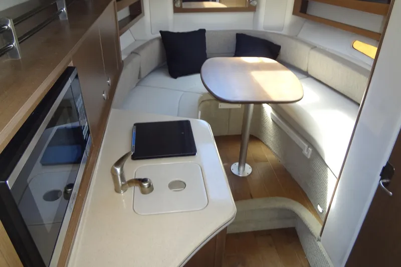 Slide: The Image of 2017 Sea Ray Sundancer 280 interior with kitchenette, seating area, and table. - 28