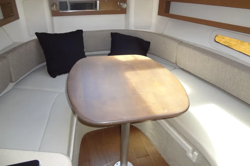 Slide: The Image of 2017 Sea Ray Sundancer 280 interior with cushioned seating and wooden table. - 29