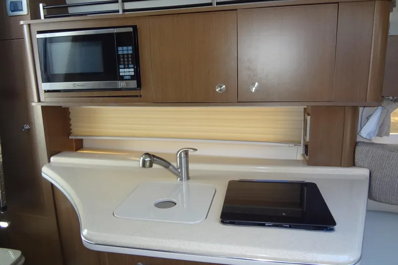 Slide: The Image of 2017 Sea Ray Sundancer 280 galley with microwave, sink, and modern cabinetry. - 31