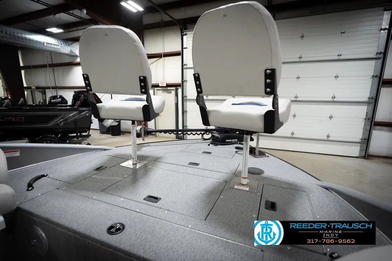 Slide: The Image of Two white boat seats on a gray deck in a showroom, Reeder-Trausch Marine logo visible. - 28