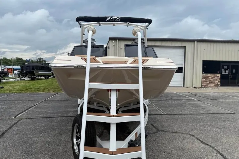 Slide: The Image of 2024 ATX Surf Boats 24 Type-S on trailer, parked outside a building under cloudy skies. - 3