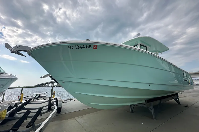 Slide: The Image of 2023 Robalo R302 Center Console boat on trailer, dockside under cloudy sky. - 2