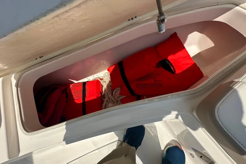 Slide: The Image of Storage compartment with red life jackets on a 2023 Robalo R302 Center Console boat. - 24