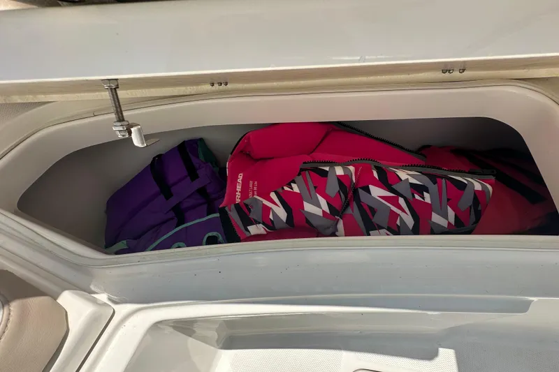 Slide: The Image of Storage compartment with life jackets on a 2023 Robalo R302 Center Console boat. - 25