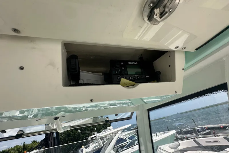 Slide: The Image of 2023 Robalo R302 Center Console boat with Simrad marine radio in storage compartment. - 29