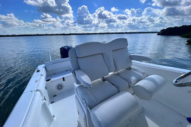 Slide: The Image of 2017 Sea Hunt Ultra 235 SE boat with white seating on a calm lake under a cloudy sky. - 12