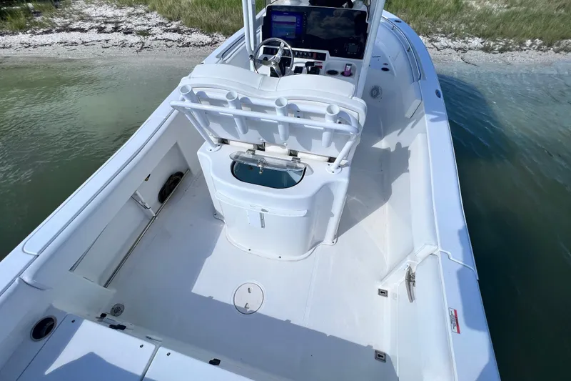 Slide: The Image of 2017 Sea Hunt Ultra 235 SE boat interior with helm and seating, near shoreline. - 16