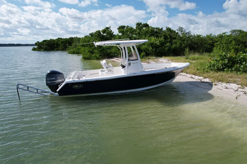 Slide: The Image of 2017 Sea Hunt Ultra 235 SE boat anchored on a sandy shore with lush greenery. - 3