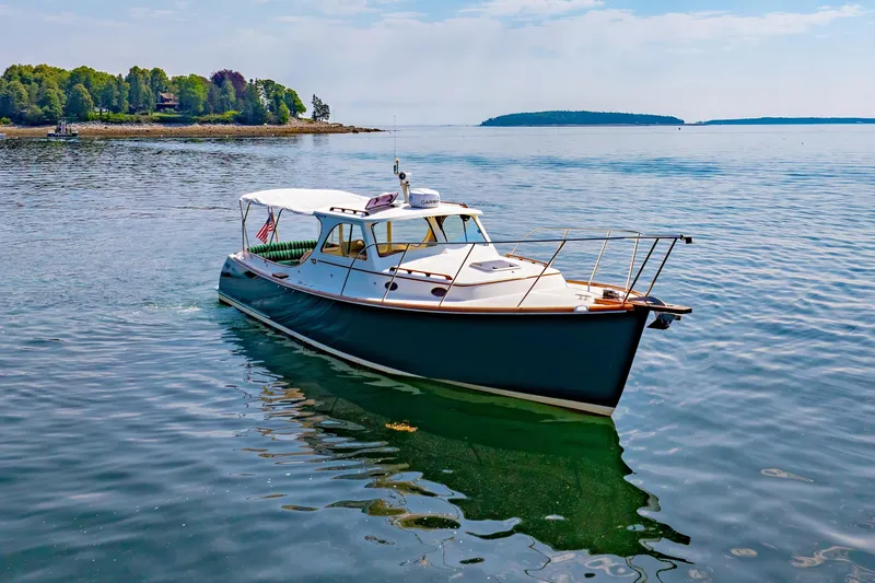 Slide: The Image of 1999 Hinckley Picnic Boat cruising on calm waters near a scenic shoreline. - 12