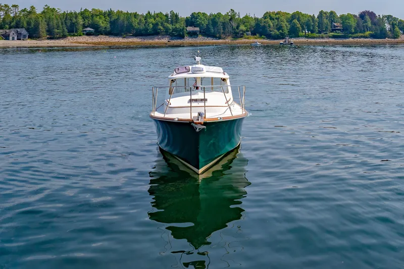 Slide: The Image of 1999 Hinckley Picnic Boat on calm water with scenic shoreline background. - 14